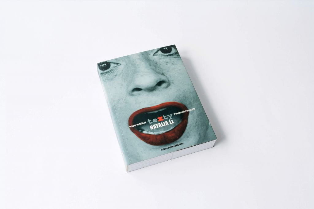 Na białym tle książka, na okładce kobieca twarz – w ustach pomalowanych na czerwono widnieje napis Natalia LL