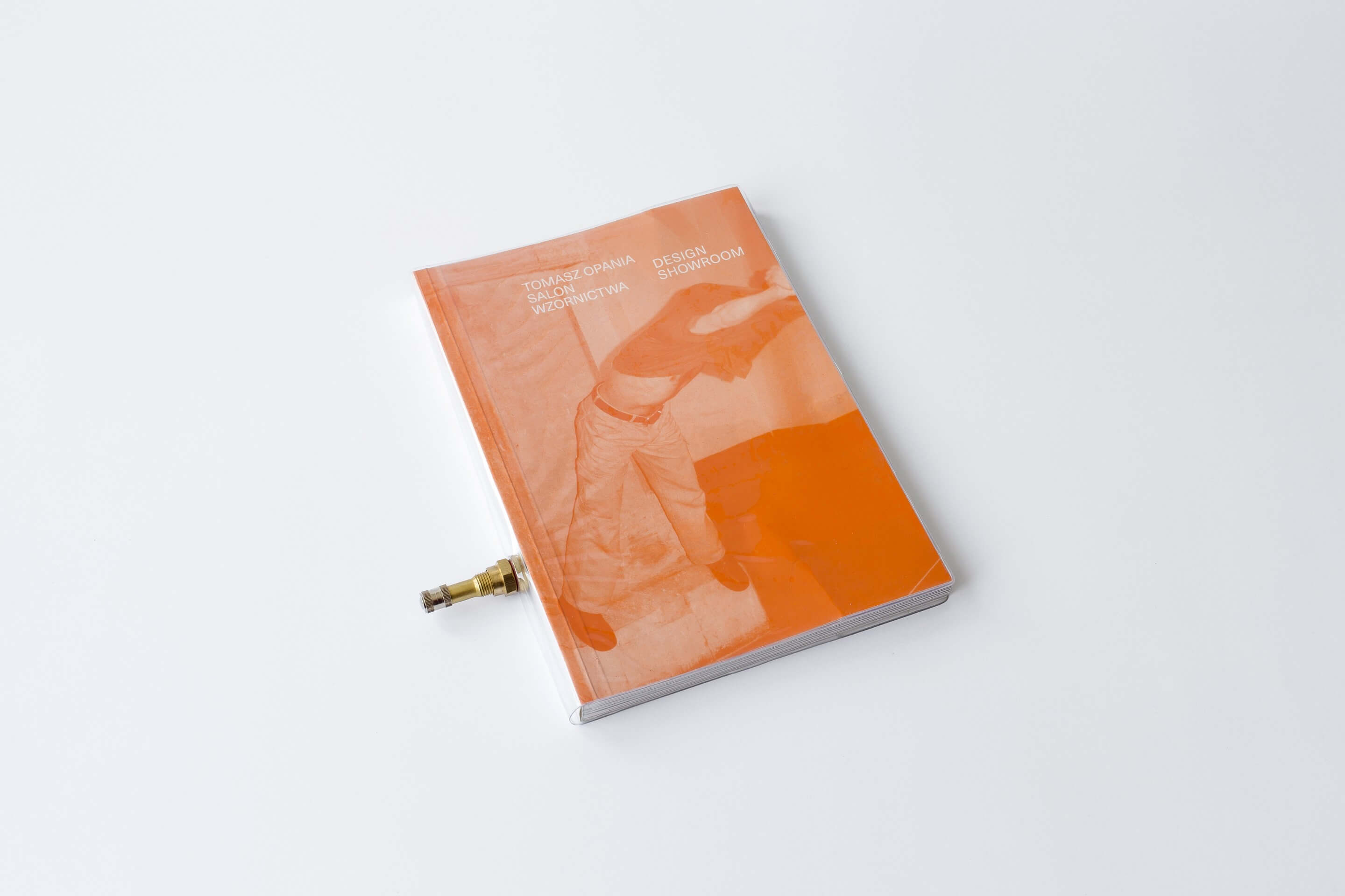 Na białym tle pomarańczowa książka oprawiona w folię, z zaworem do pompowania.