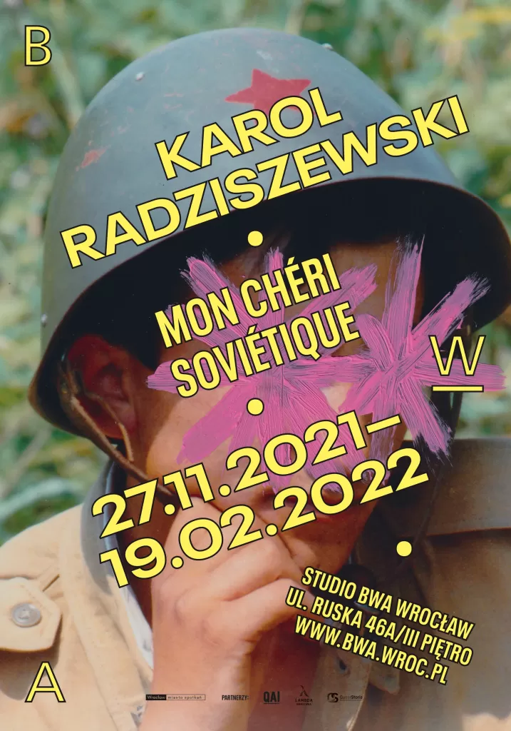 Plakat wystawy Mon Cheri Sovietique. Zdjęcie mężczyzny w wojskowym kasku, na jego twarzy namalowana jest różowa gwiazda.