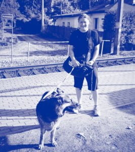 niebieskie zdjęcie przewodniczki po wystawie, Agaty Kalinowskiej z dużym psem rady owczarek niemiecki