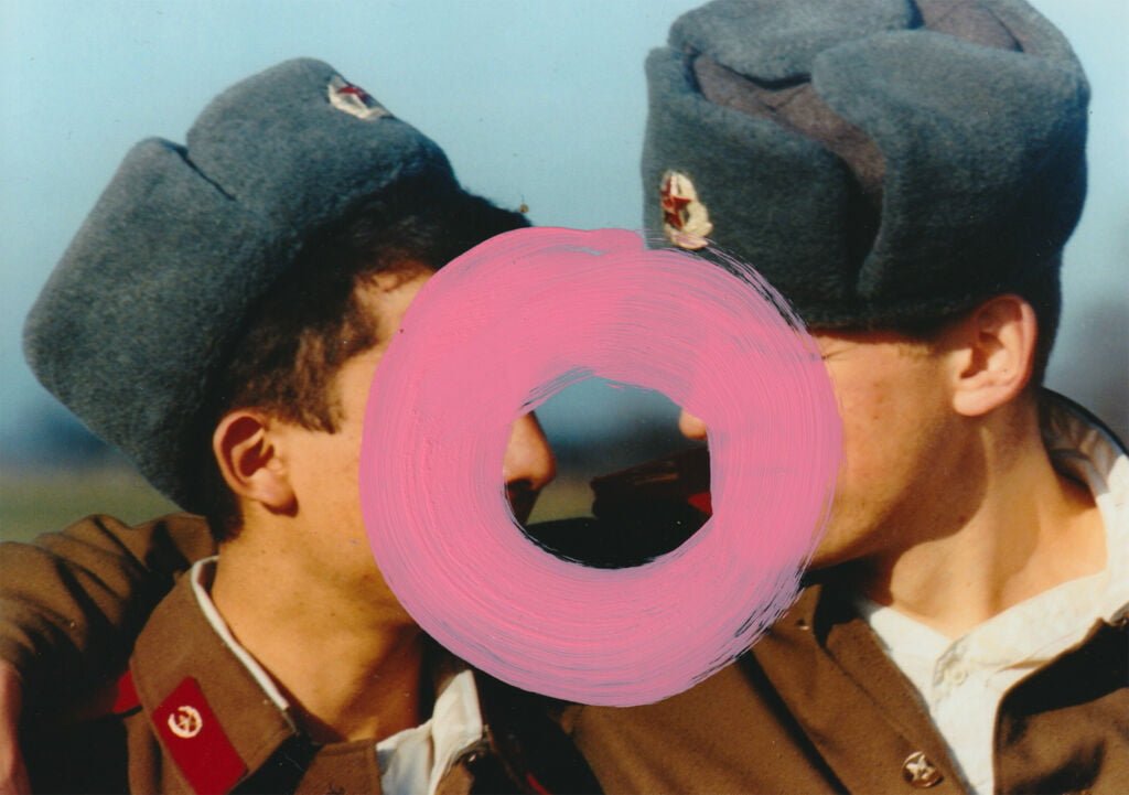 portret dwóch młodych żołnierzy sowieckich w mundurach, którzy patrzą się na siebie z bliska, jakby zbliżali się do pocałunku. na środku zamalowane różowe koło, aby ukryć ich tożsamość