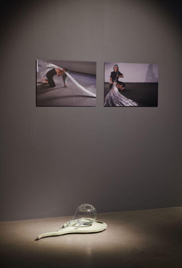 zdjęcie wnętrza galerii, dwie fotografie i szklana rzeźba
