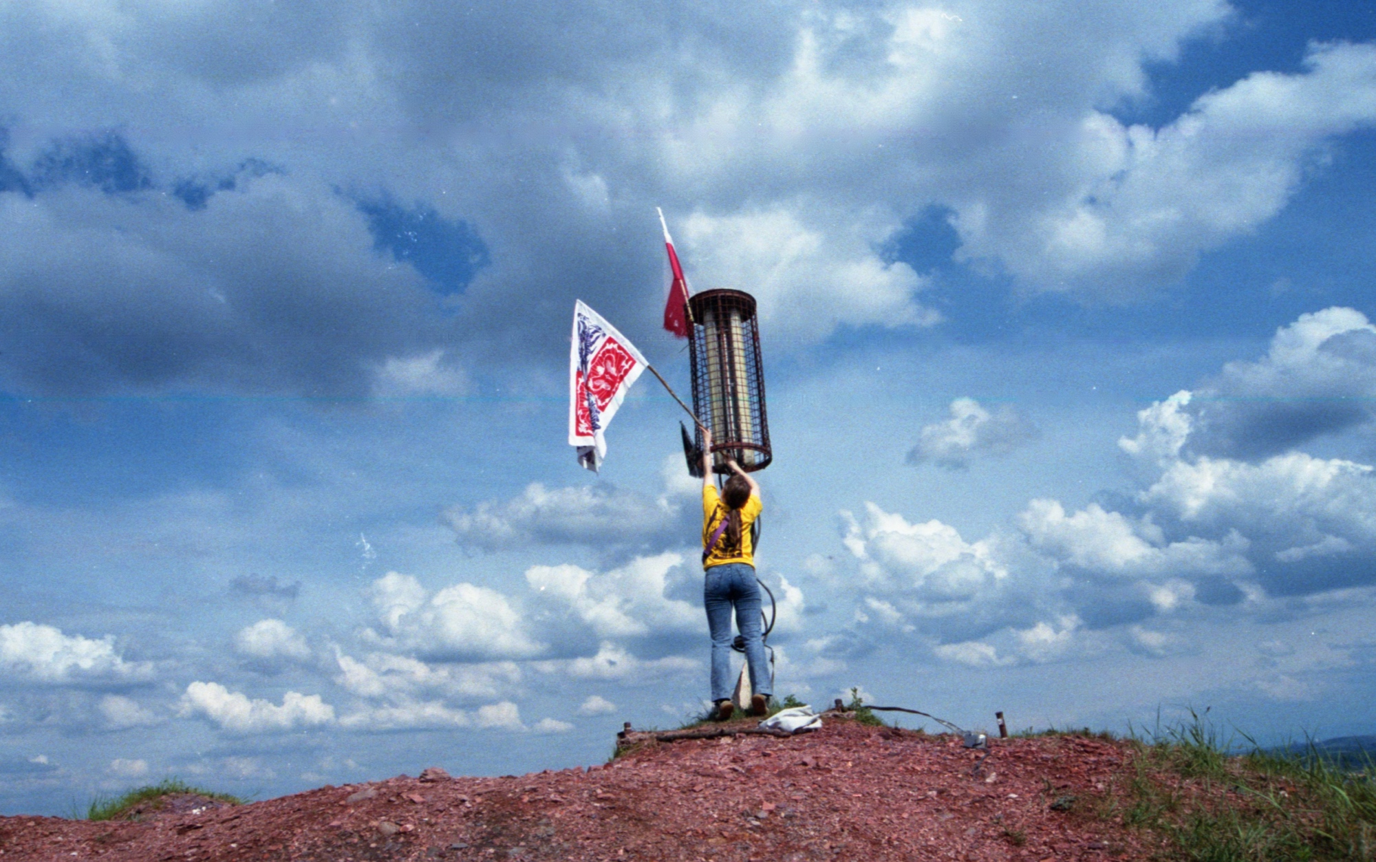 osoba na wzgórzu trzymająca flagę