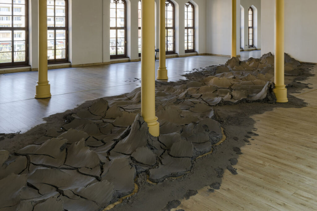 Rzeka wyrzeźbiona z gliny, wzdłuż długiej sali wystawowej z kolumnami