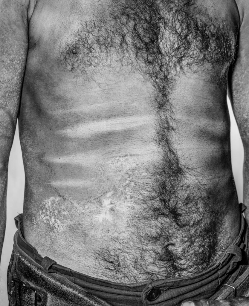 Photo of the torso of a middle-aged man, soiled with coal dust.
