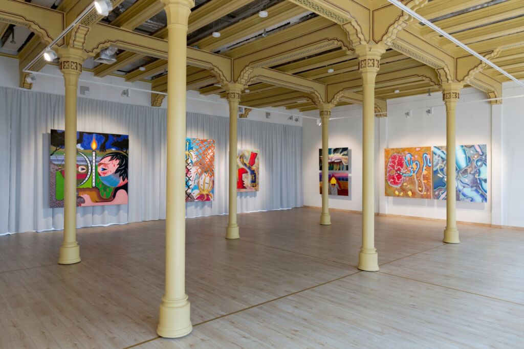 gallery space with columns, paintings on the walls