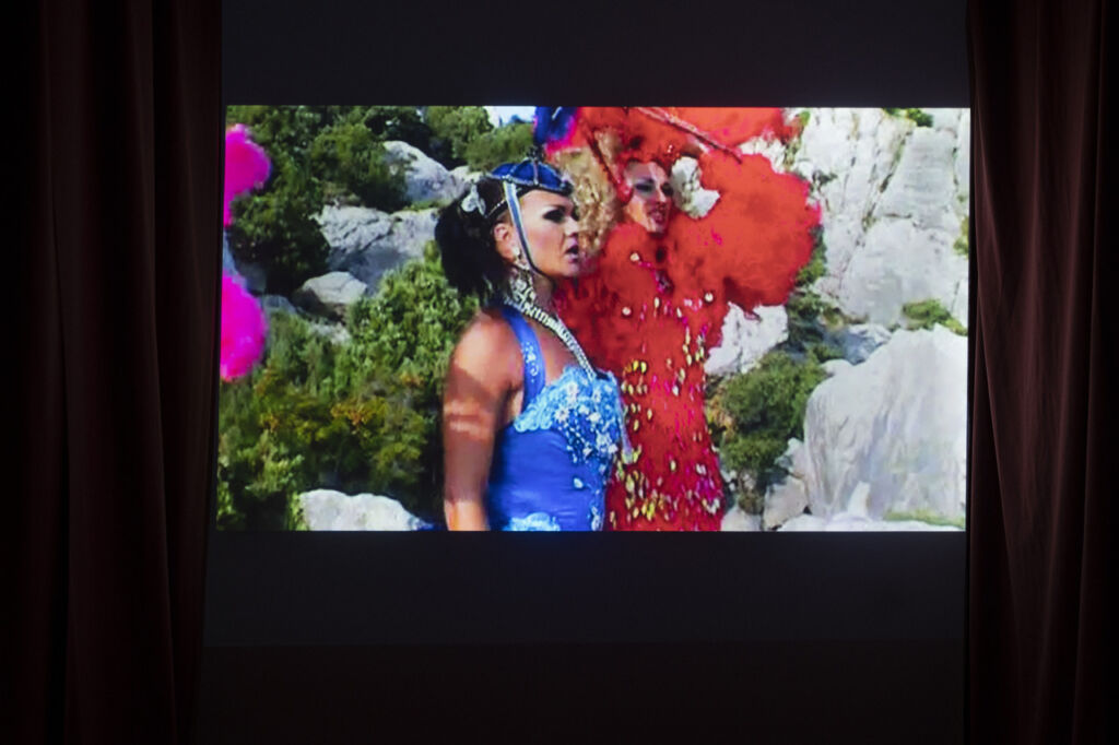ekran z wyświetlaną pracą wideo, w kadrze widać dwie postaci ubrane w kolorowe stroje