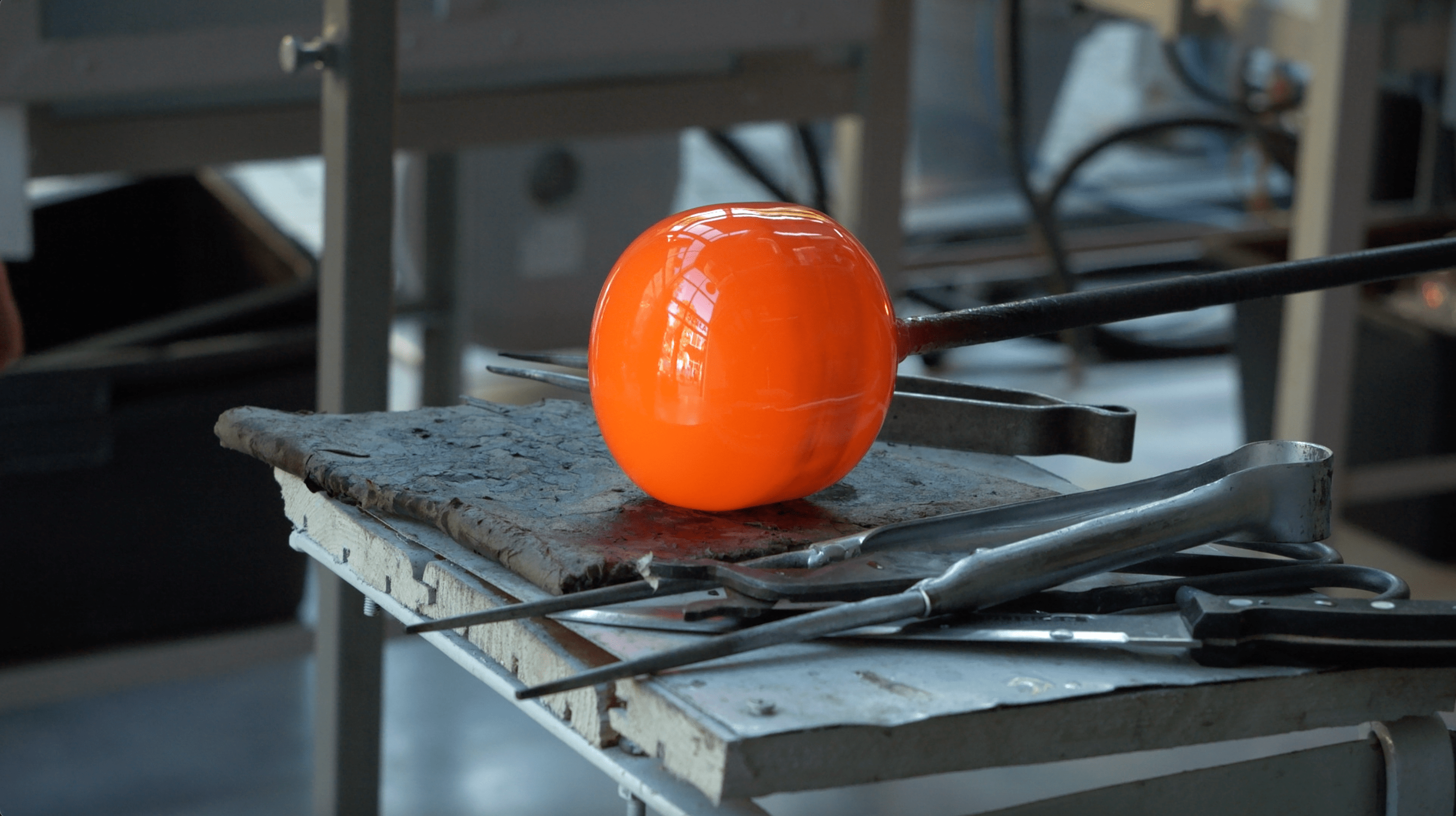 Pomarańczowa szklana kula siedzi na stole.