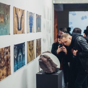 Grupa ludzi oglądających dzieła sztuki wystawione w galerii sztuki.