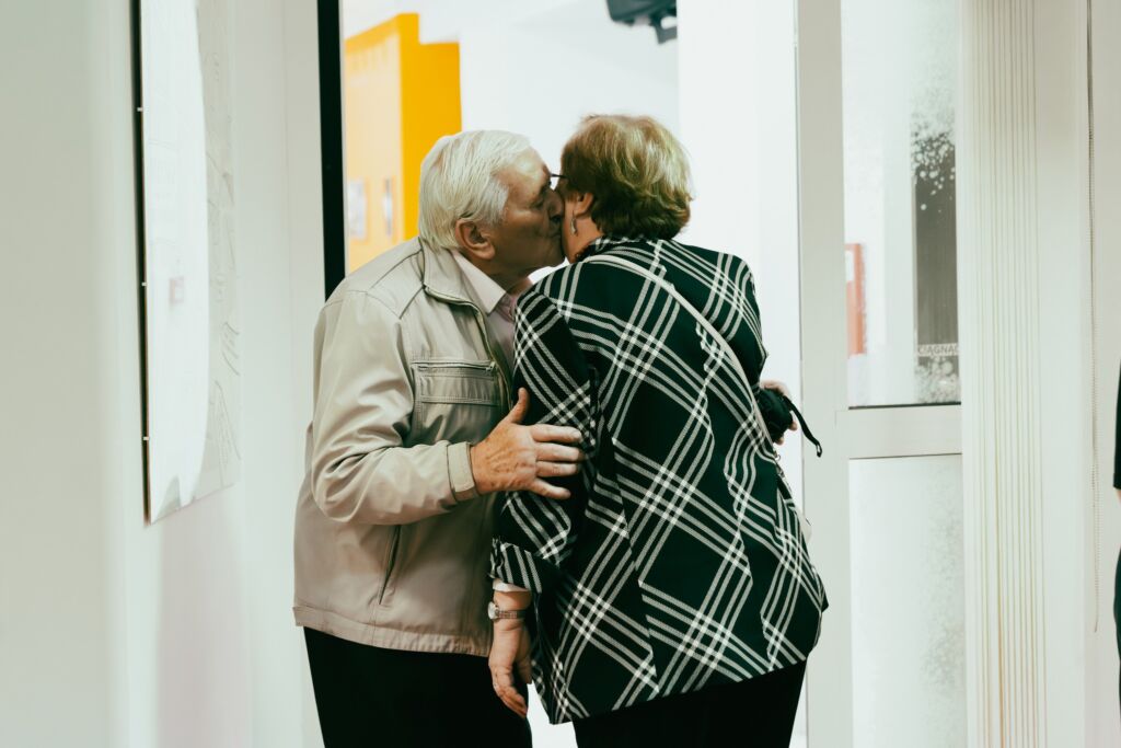 Starszy mężczyzna i starsza kobieta witają się pocałunkiem w przestrzeni wystawy