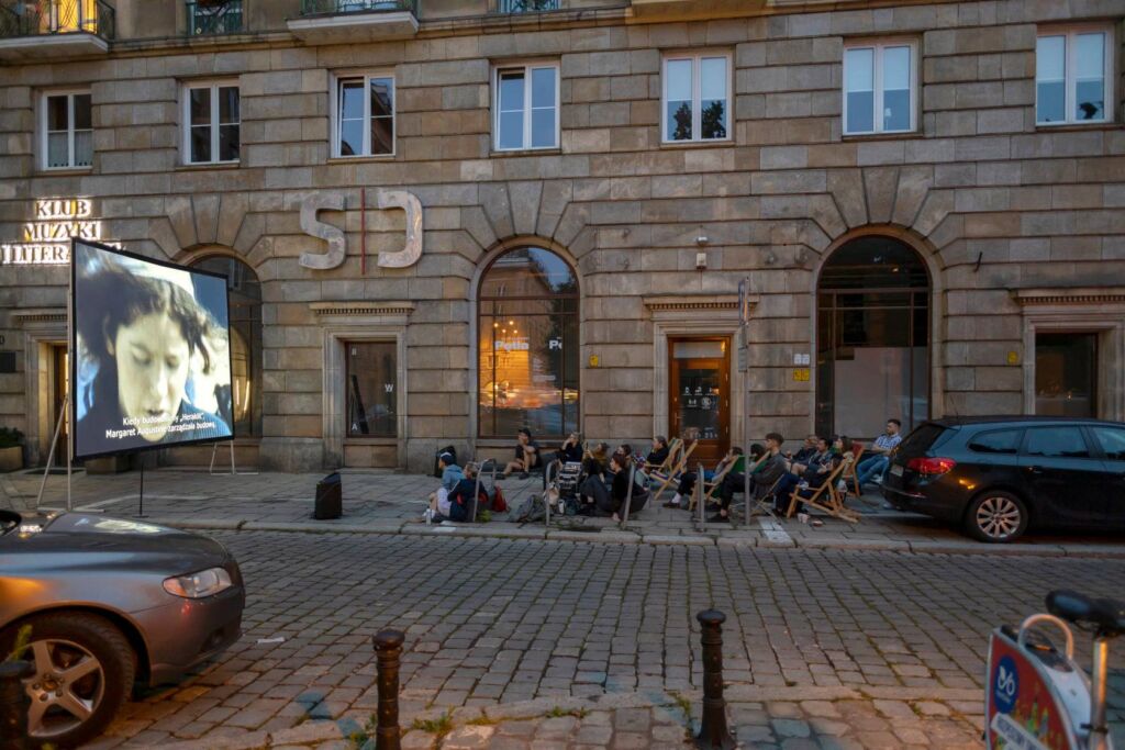 Ludzie siedzący na leżakach przy kinie plenerowym na pl. Kościuszki