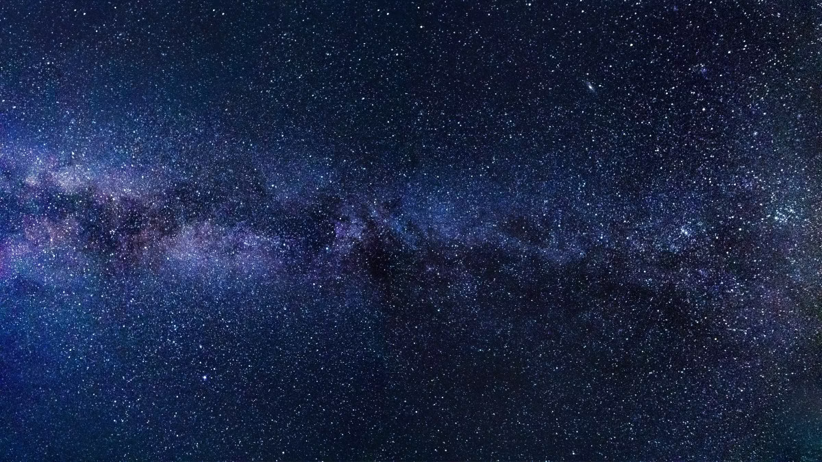 Wyraźny widok nocnego nieba ukazujący galaktykę Drogi Mlecznej z niezliczonymi gwiazdami rozrzuconymi na ciemnoniebieskim tle.