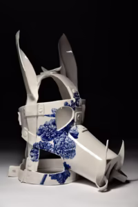 Porcelanowa rzeźba przypominająca zwierzęcą maskę z kwiatowymi niebieskimi wzorami i spiczastymi uszami, z misternymi detalami i błyszczącym wykończeniem.