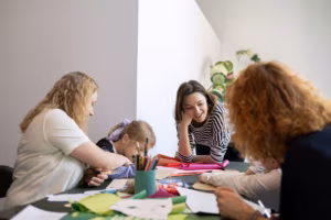 Kobieta i dzieci pracujące razem nad projektem rękodzieła przy stole.